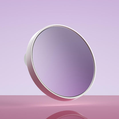 Fancii Tara 10x Magnifying Mirror with white frame and suction mount, floating against a purple background.