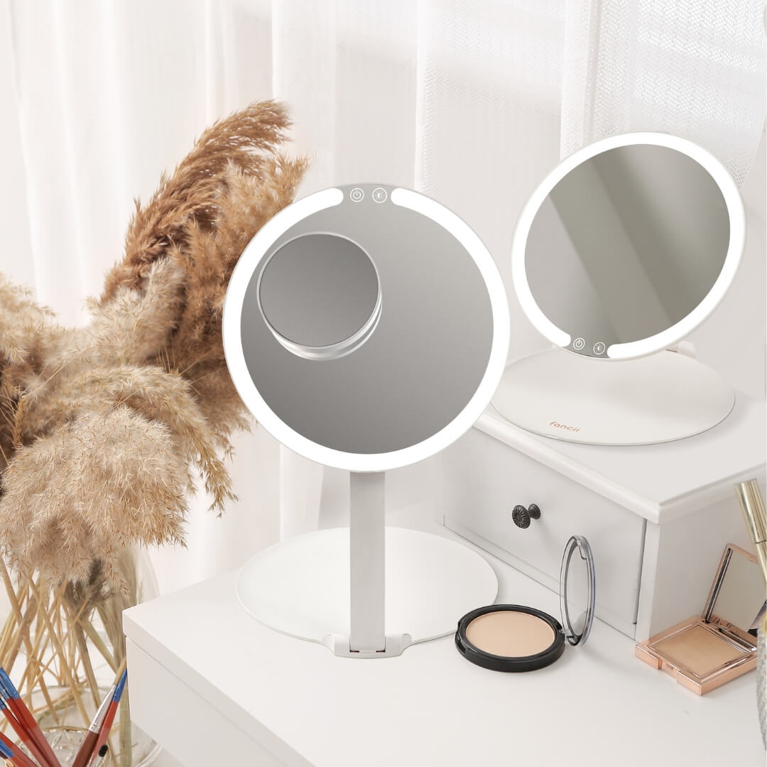 Tara 10x Magnifying Mirror attached to a larger lighted makeup mirror on a vanity for clear, detailed views.